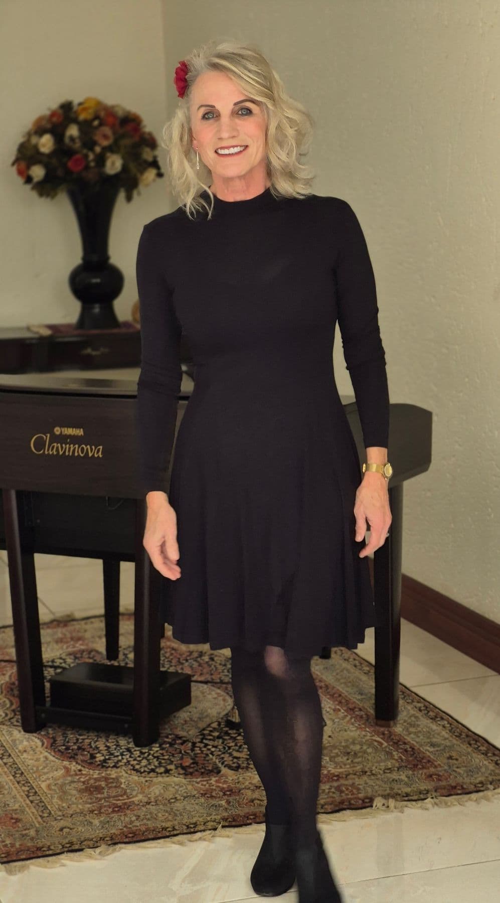 Esmé Bergh in a black dress with a red flower in her hair, standing in front of a digital piano
