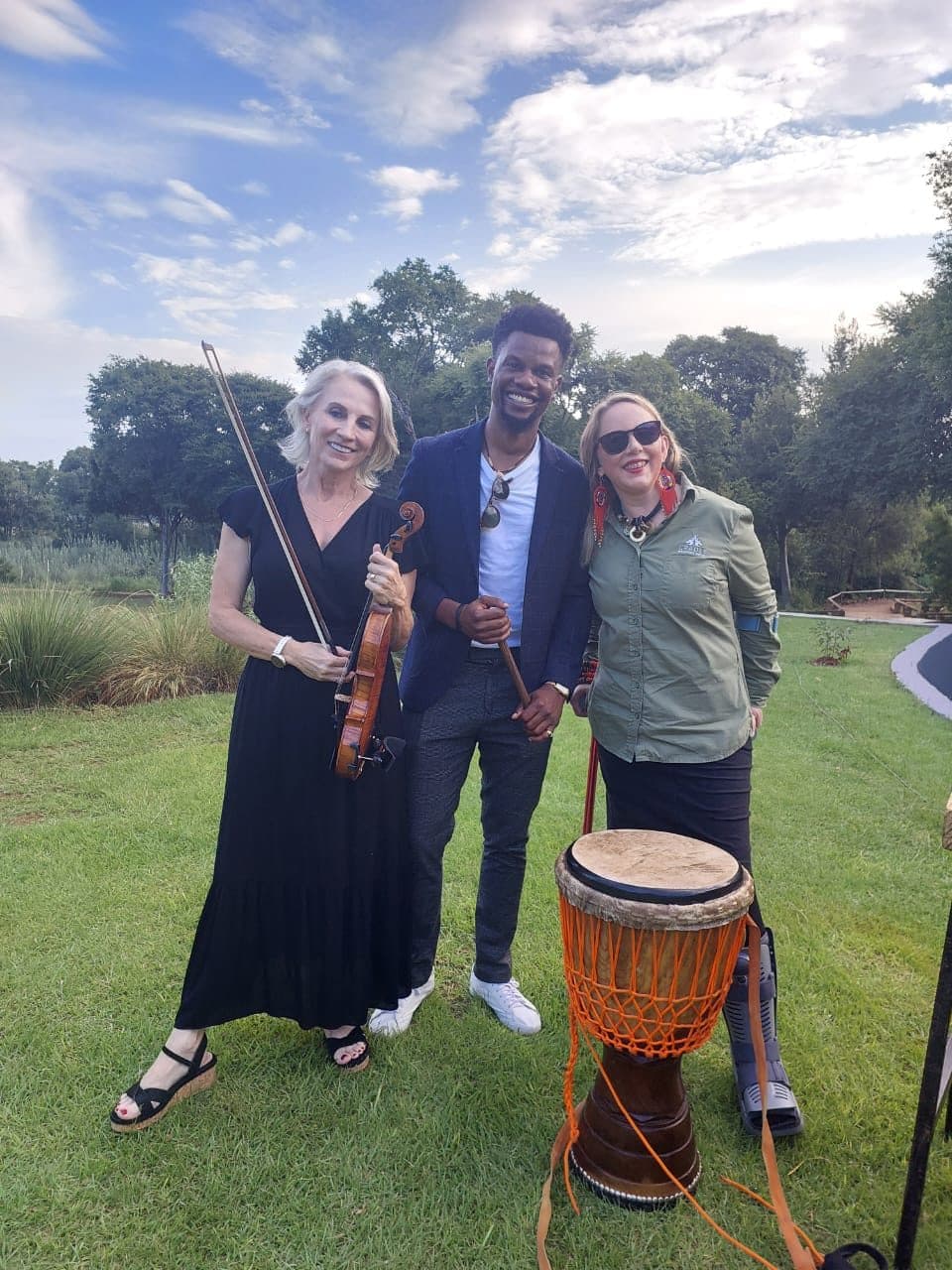 Esmé Bergh standing outdoors with two other musicians, one of them holding a djembe